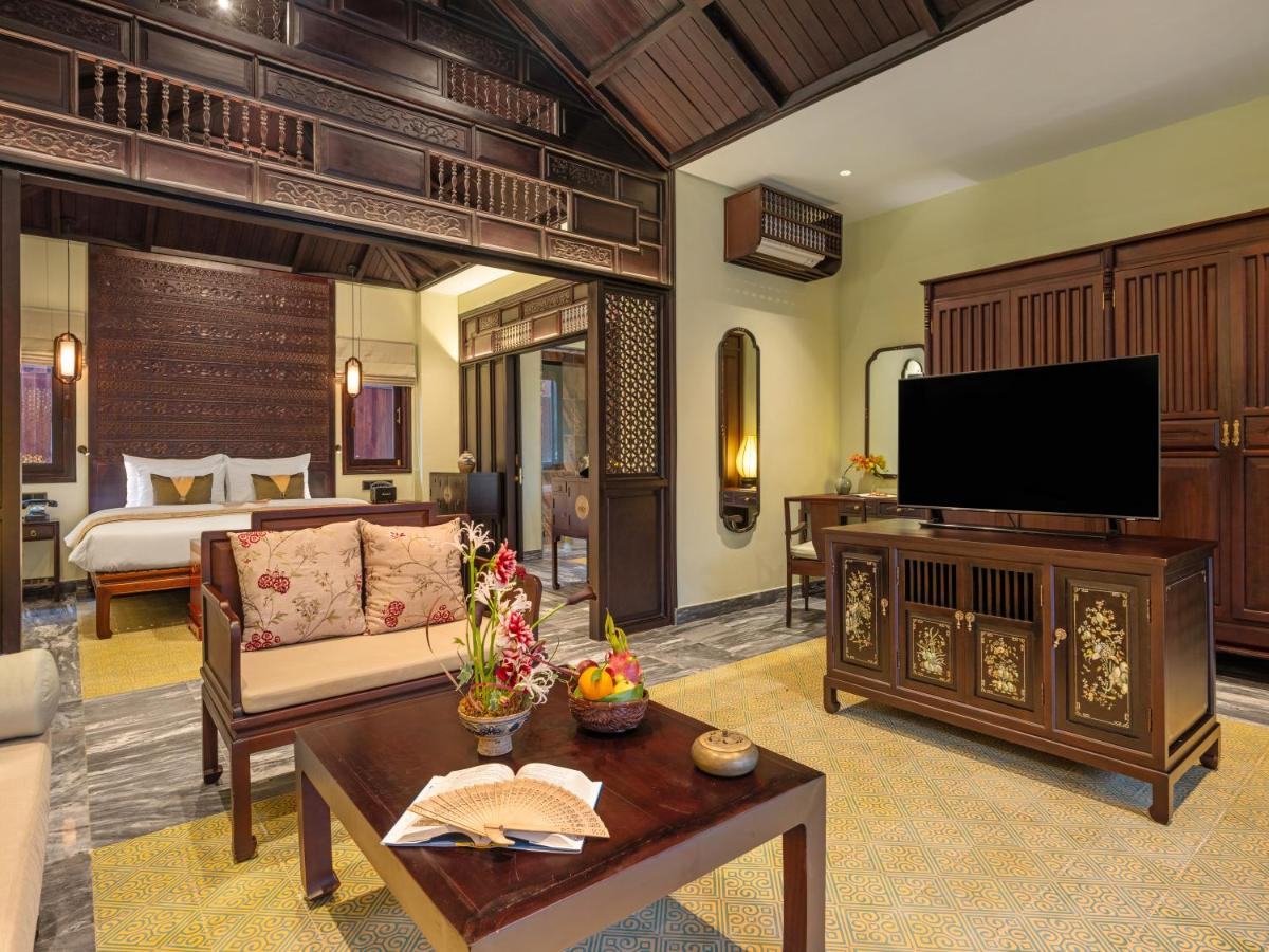 Spacious garden-house room with a sitting area, carved wooden furniture, a television cabinet and yellow-tiled floor